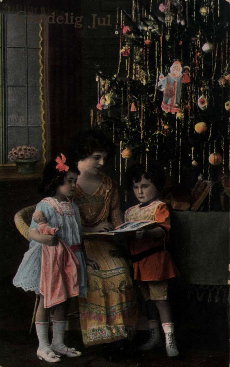 Julekort. Jule- og nyttårshilsen. Mor leser for to barn foran et pyntet juletre. Stemplet 21.12.1916.