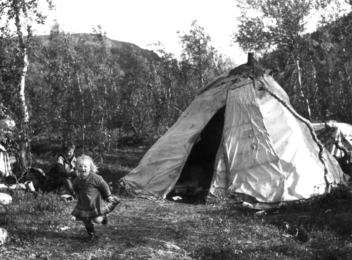Sommerboplass tilhørende Klemet Buljo (Lemun Lemet). En liten jente løper foran teltet som har ovn.  Nibijavrre 1972.