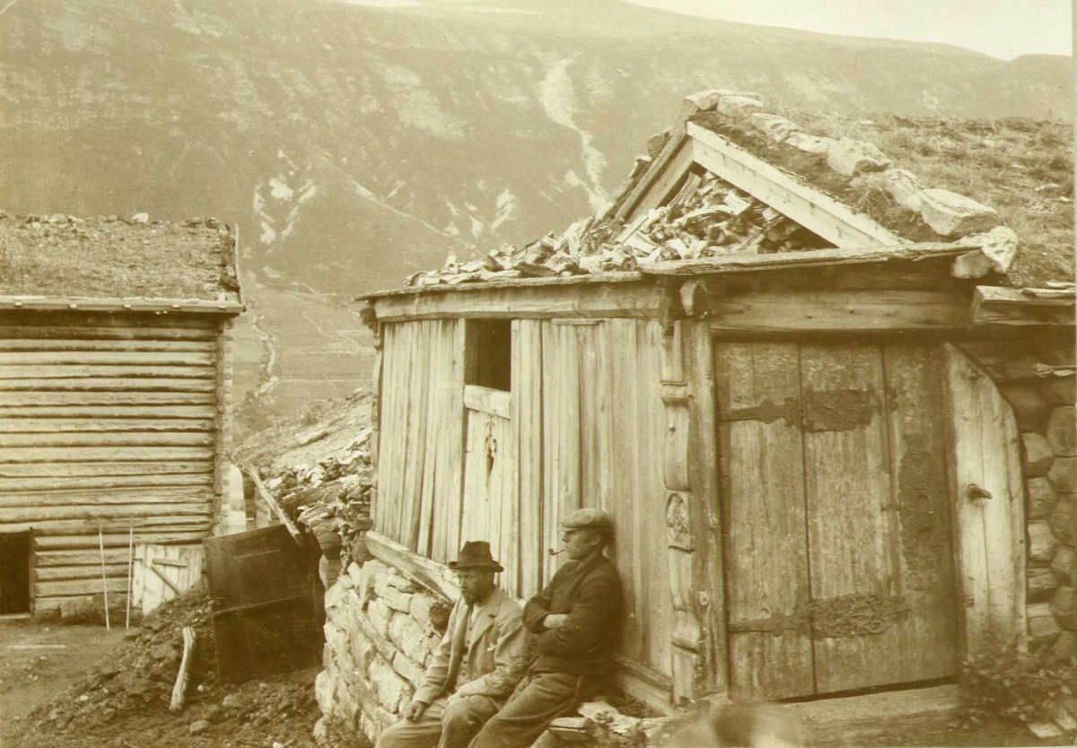 Fjøssval, Ramstad - (midtre Ramstad (Meramstad), Skjåk, Oppland. To menn sitter i forgrunnen. Fotografert 1908.