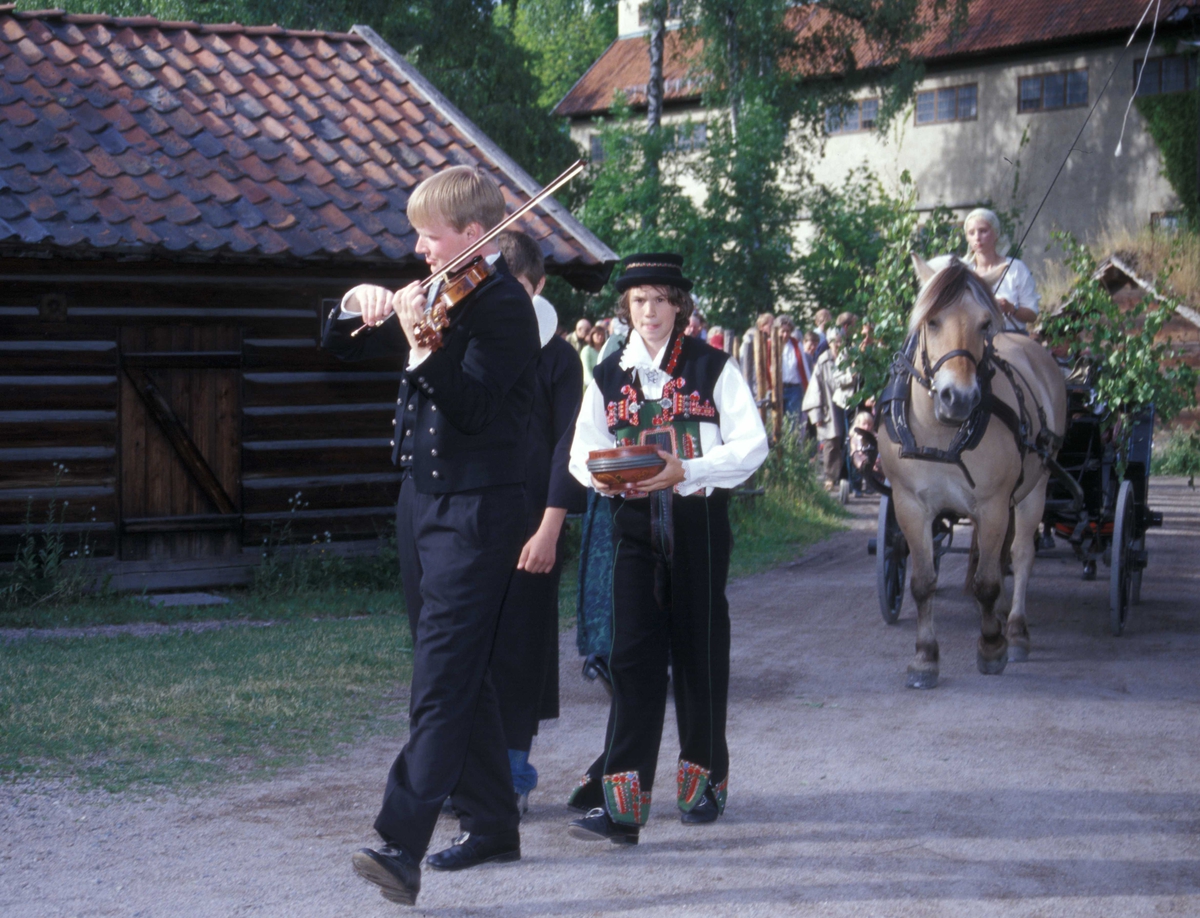 St. Hansaften og jonsokbryllup på Norsk Folkemuseum 2004. Her brudefølget med spillemann  i spissen., kjøgemesteren og vognen med  det unge paret.
