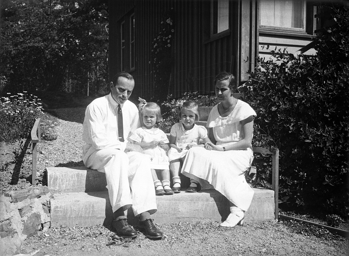 Søstrene Siri og Guri Arentz sitter sammen med sine foreldre Dordi og Fritjof på en trapp i hagen, Bygdøy. Fotografert 1933.