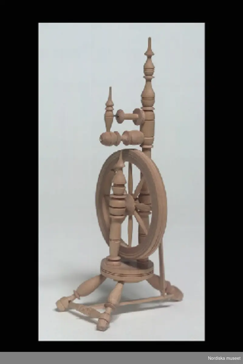 Inventering Sesam 1996-1999:
H 18  B 7  (cm)
Spinnrock, högrock leksak, av svarvat obehandlat lövträ, tre ben infästade i rund bottenplatta, spinnhjul med trampa, spole  och rockhuvud.
Birgitta Martinius 1997
