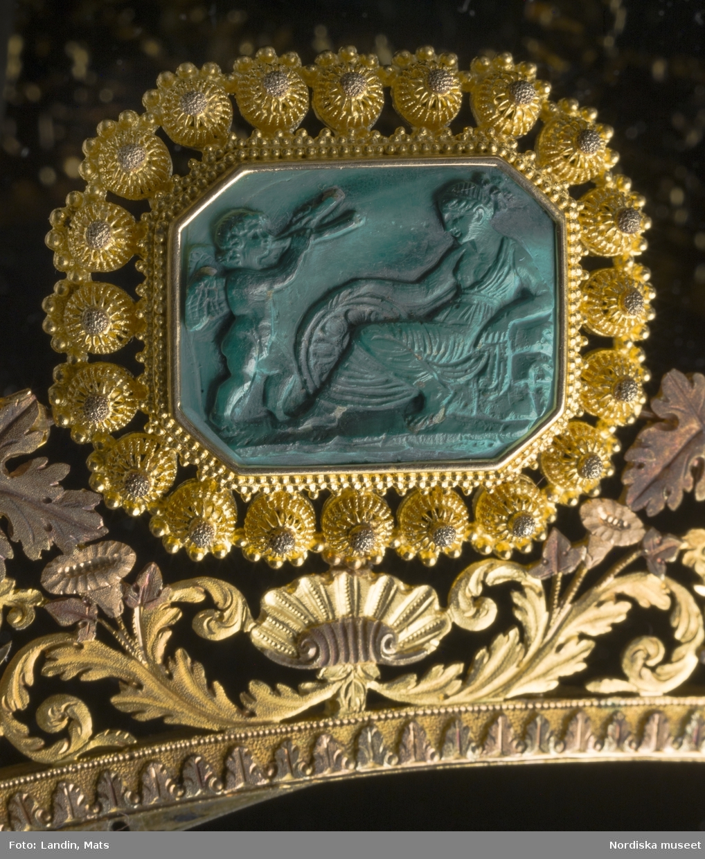 Smycken. Drottning Sofias garnityr utfört av guld och malaktit. Nordiska museets föremål Inv nr 990047.

Garnityret har tillhört Sveriges och Norges drottning Sofia (1836-1913).  Kaméerna är är skulpterade av det ovanliga smyckematerialet malakit, en grön kopparhaltig sten. De antika motiven är inspirerade av den danske skulptören Bertel Thorvaldsens bildvärld. Garnityr var vanliga under 1800-talet och var högsta mode då det användes av drottningen. Garnityret är tillverkat av Simon Petiteau, 

Se även relaterade poster/objekt.