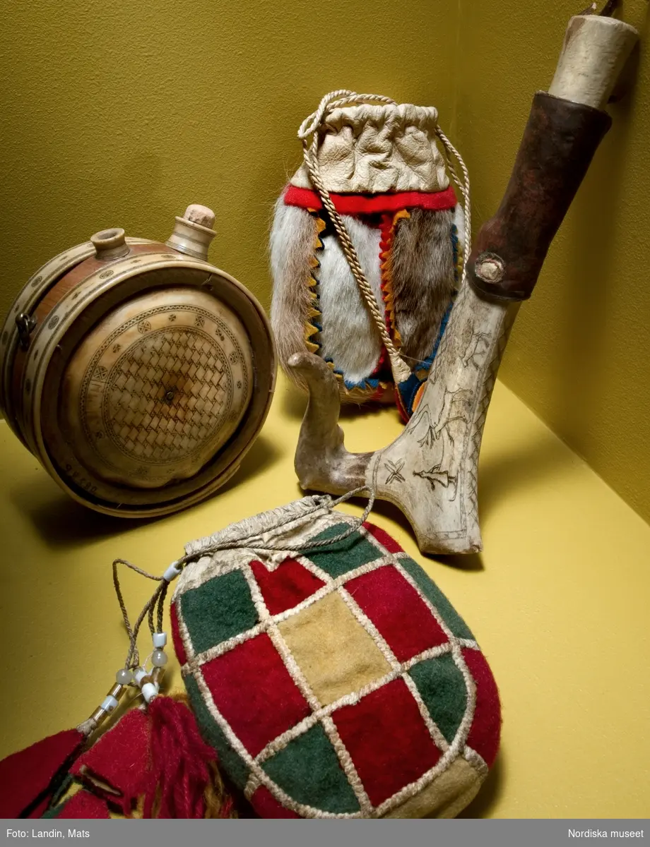 Folkkonst i utställning. Samiska föremål i Nordiska museets samlingar. Krutflaska och kniv med slida av horn. Pungar av renskinn och tyg.