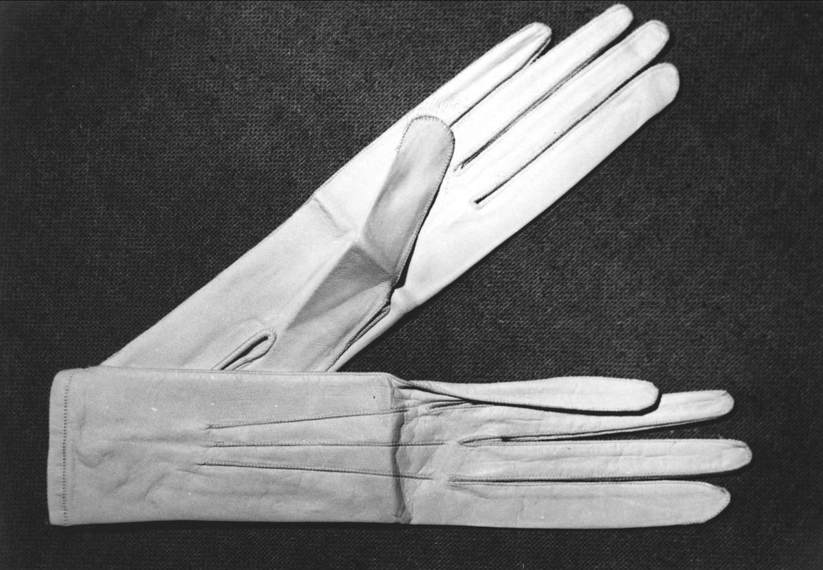 Två par vita glacéhandskar. Sprund vid handleden knäppt med knapp och knapphål Stämpel inuti en av handskarna: 10.6 3/4.
