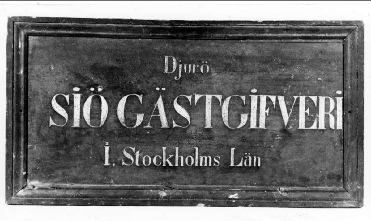Skylt av svartmålat trä med text i vitt: Djurö SJÖGÄSTGIVERI I Stockholms Län.


