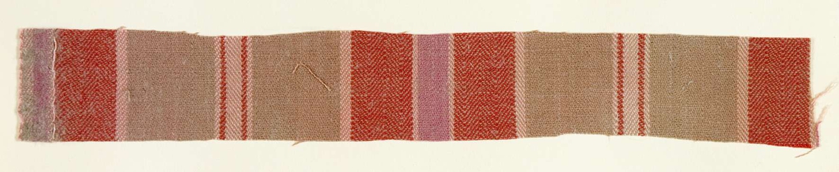 Vävprov ämnat för bolstervarstyg, spetskypert. Randigt i rött, rosa och beige. Vävprovet är uppklistrat på en kartong i storleken 22 x 28 cm. I övre högra hörnet finns en stämpel "Uppsala läns hemslöjdsförening" och ett handskrivet nummer, "A.1586".