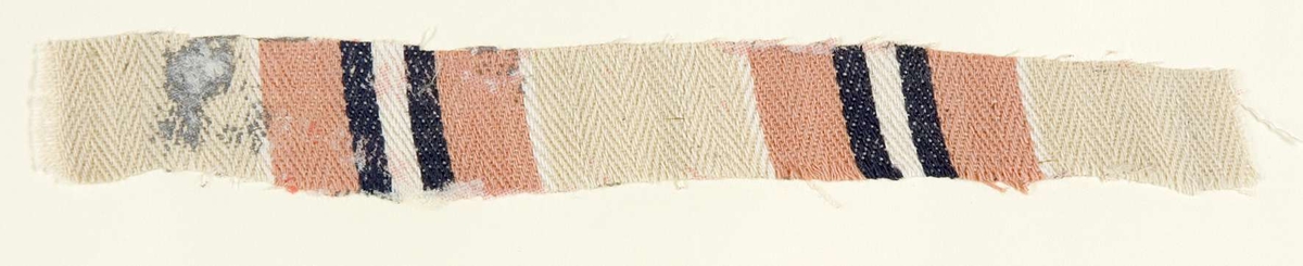Vävprov ämnat för bolstervarstyg, spetskypert. Randigt i rosa, beige och mörkblått. Vävprovet är uppklistrat på en kartong i storleken 22 x 28 cm. I övre högra hörnet finns en stämpel "Uppsala läns hemslöjdsförening" och ett handskrivet nummer, "A.1588".