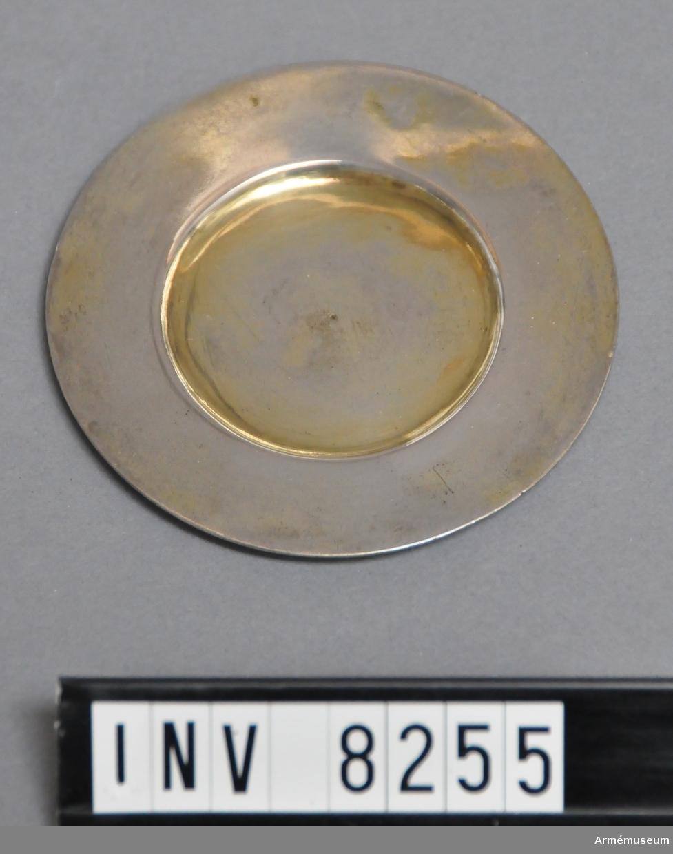 Fatet är förgyllt på båda sidor. Märkning åldermannaranka = föremålet tillverkat före 1754, p=1727. HNW=Hans Eriksson Nordwall. Stadsvapnet för Stockholm 1727. Märkt dessutom med ett tunt verktyg "3 1/4" på undersidan av fatet.