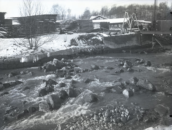 "1935. 28. Bron sönder vid Munkedals fabrik."
"Munkedalsälven. Emballagevirke i buntar, liten såg, gavelspetsen på arbetarbostaden i bakgrunden."