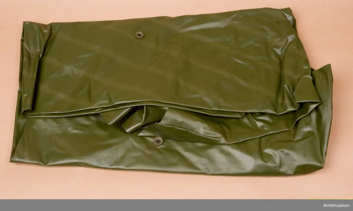 Regnskydd arbm/1967.Av olivgrön plast med hål för huvudet och med knäppanordningar för tält.