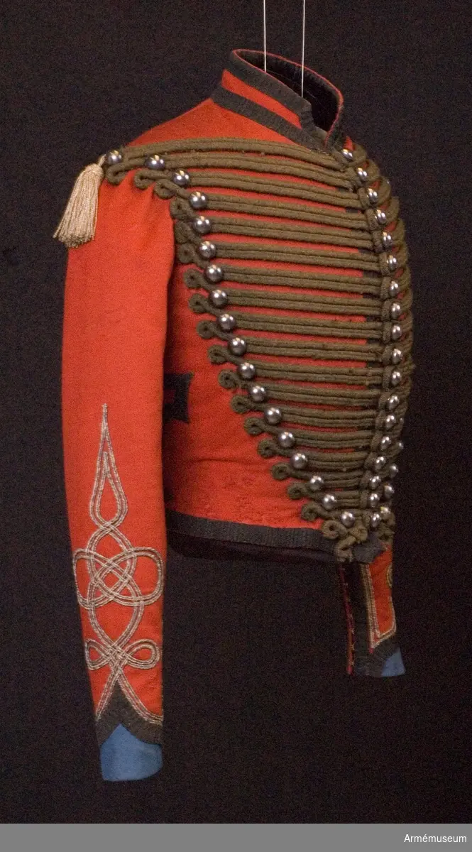 Grupp C I.
Dolma tillhörande uniform för officer vid Ridande jägare, Frankrike.
Uniformen består av dolma m/1859, långbyxor och högmössa.
Dolma är av rött kläde med ståndkrage. Dolman är kort -  midjelängd - enkelknäppt med 18 kullriga knappar, 18 i varje rad. Mellan dessa knappar horisontellt svarta runda knäppsnören med en ögla på ena sidan och med knapparna och knapphålen på den andra. På ryggens båda sidor finns beläggningar av svarta snören och svarta bomullister. Foder av vitt sidentyg med 8 cm breda lister av grönt läder vid dolmans nedre kant. Kragen är fodrad med svart sammet. Knapparna är av vit metall: 18 kullriga mitt på bröstet och 18 halvkullriga på böstets båda sidor. Alla 2 cm i diameter. Kragen av samma röda tyg med två svarta bomullslister - 2 cm breda vid övre och nedre kanten. Tofsar på båda axlarnas sidor vid övre knapparna. De är gjorda av silversnören. Ärmuppslagen har triangelform av blått tyg med svarta redgarnsband - 2 cm breda - och med silversnören omkring. Ärmuppslagen har ett sprund med 11 par hyskor och hakar 1 cm samma svarta redgarnsband och snören omkring. Ärmuppslagen har på övre delen beläggningar i form av knutar (efter ungerska husarernas modell) av silversnören.

Litteratur Handbuch der Uniformenkunde. Prof R Knötel, Hamburg 1937 Frankrike: Jäger zu Pferde sid 178.
År 1858 under Napoleon III, hade ridande jägare svarta snören till dolma och tre rader knappar av vit metall med arton knappar i varje rad. Sedemera hade husarer vita snören på dolman och "Chasseurs a Cheval" svarta snören. Enligt kapen W Granberg.