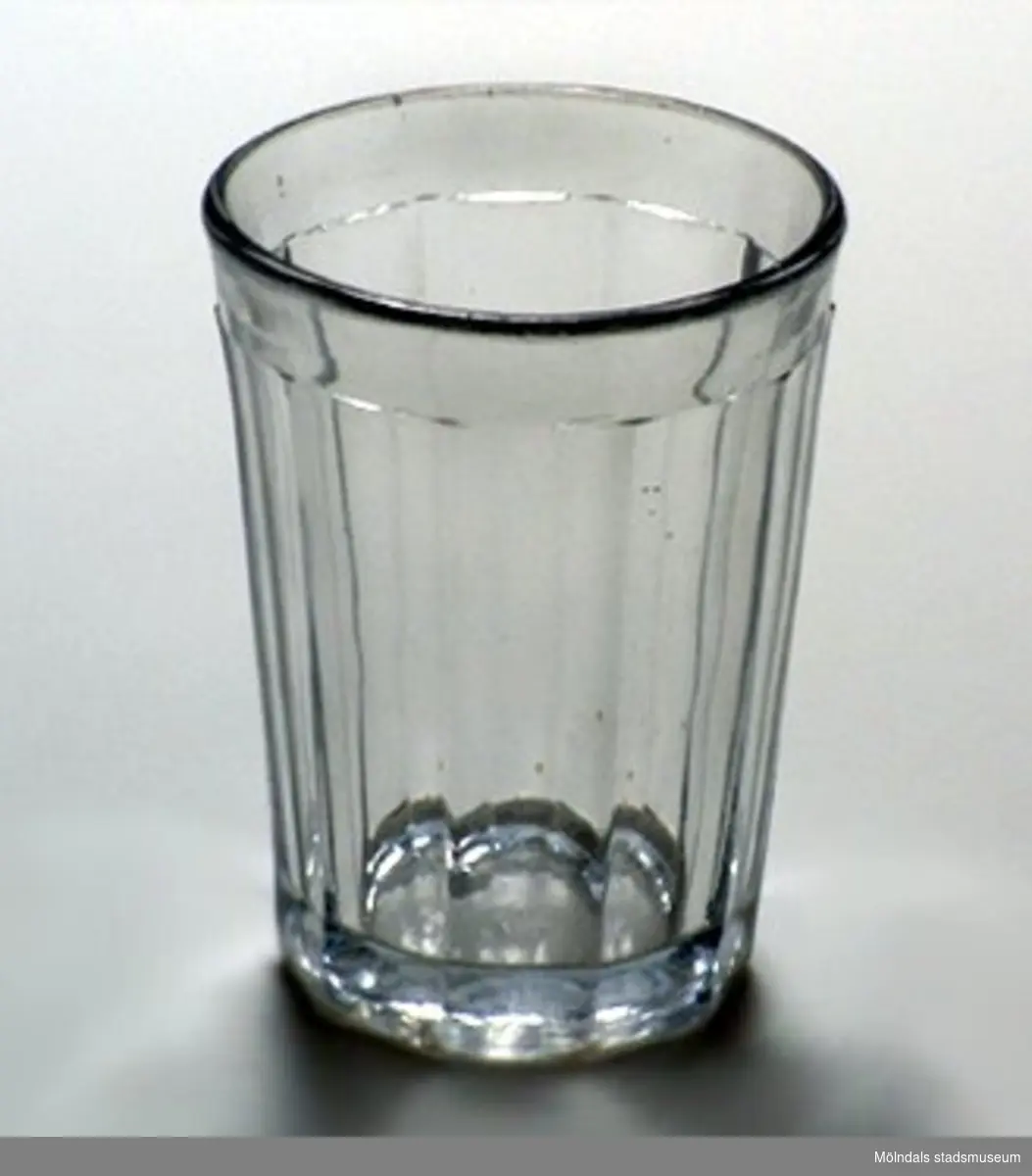 Tjockväggigt glas med starkt urslipad botten. Sidorna har vertikala plana ytor, ca 20 mm breda,  och överkanten har horisontal kant, ca 10 mm bred.
