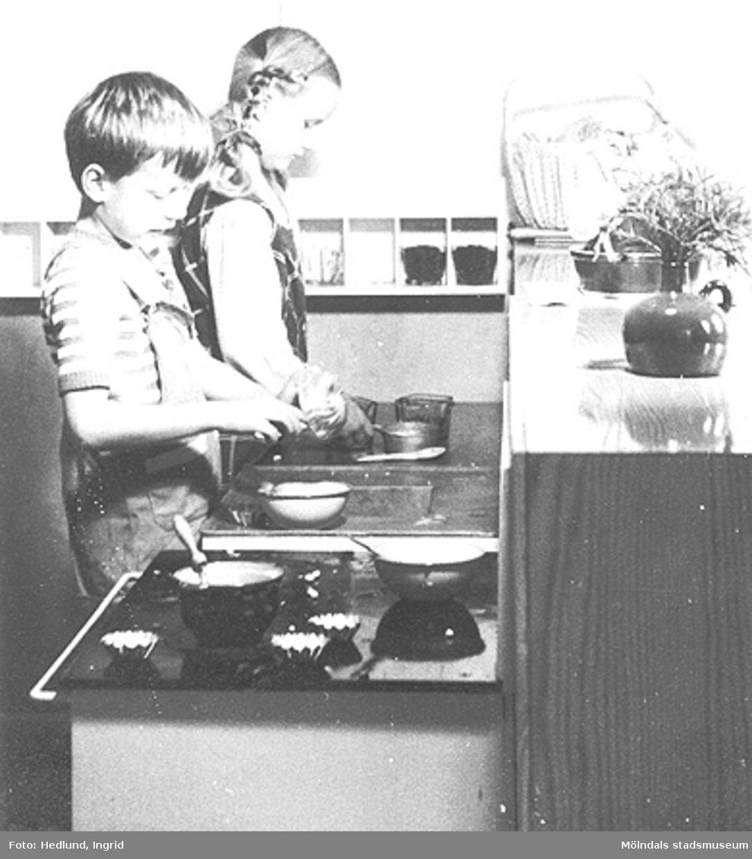 En pojke och en flicka leker att de lagar mat i ett barnkök. Daghem i Guldheden, Göteborg. Sent 1940-tal.