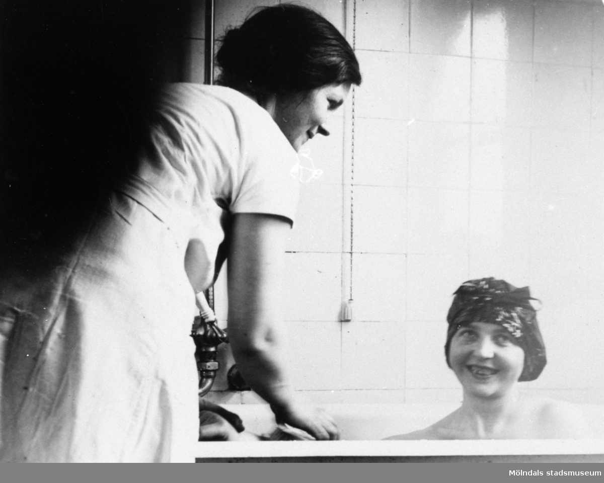 En kvinna sitter i ett badkar i Centralskolans bad (nu: Kvarnbyskolan) 1930-tal. Baderskan heter Natalia Andersson.