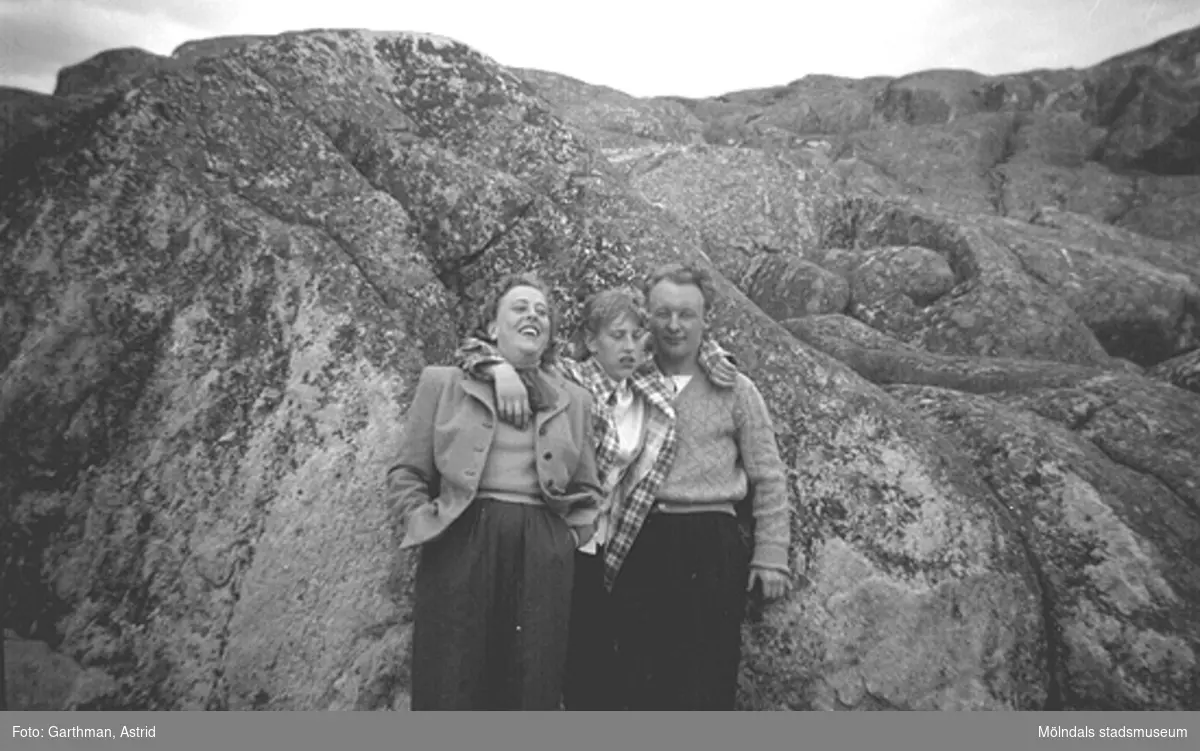 Ingrid Karlsson, Kerstin Karlsson (Astrids Garthmans syskon) och Ingrids fästman står lutandes mot en bergsknalle vid Näset, 1950-tal.