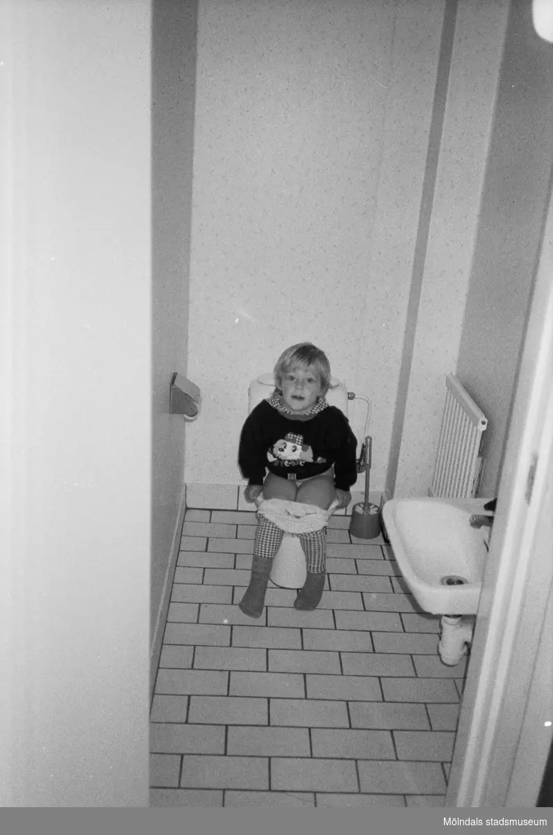 Ett litet barn sitter på toaletten i väntan på hjälp. Katrinebergs daghem, 1992-93.
