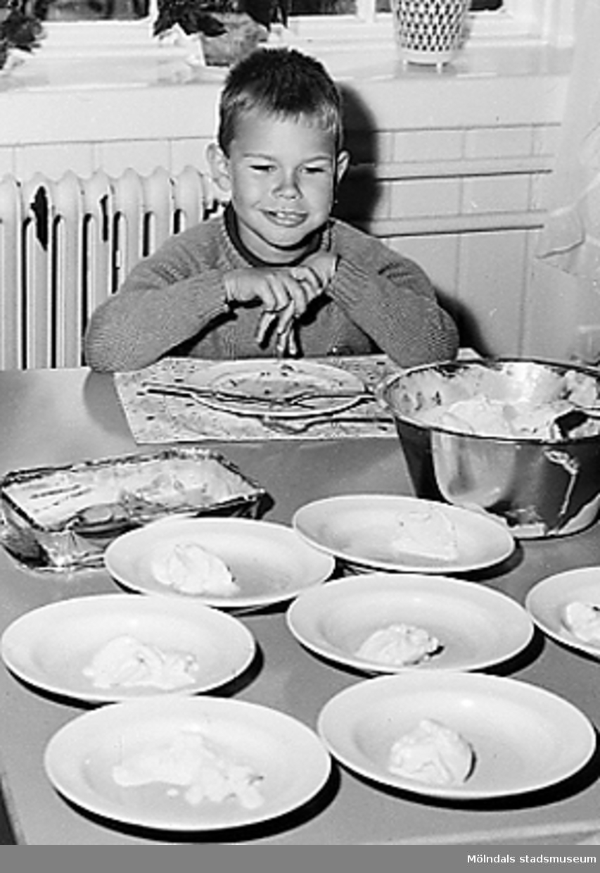 En pojke som sitter vid ett dukat matbord. Holtermanska daghemmet 1953.