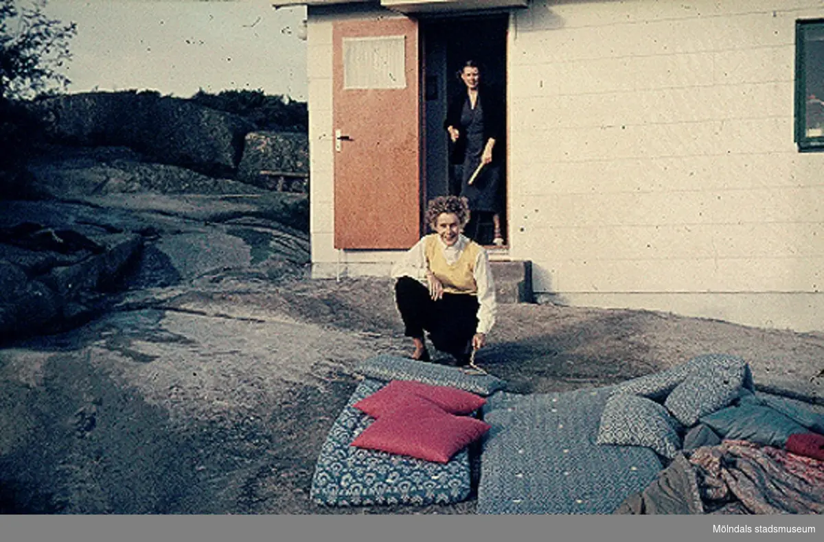 Greta och Karin Gustafsson skakar mattor vid sommarstugan på Valebergsvägen i Näset, 1956.