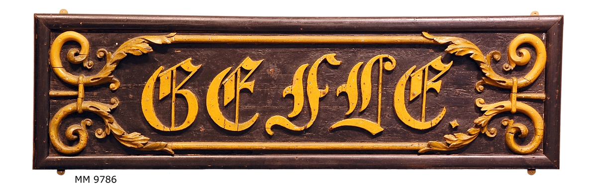 Namnbräda från ångkorvetten Gefle. (Fartyget byggt vid Örlogsvarvet Karlskrona 1847).
Försedd med namnet Gefle i skulpterade träbokstäver, omgivna av skulpterad slinga, allt gulmålat. Fäst till svartmålat träplan.