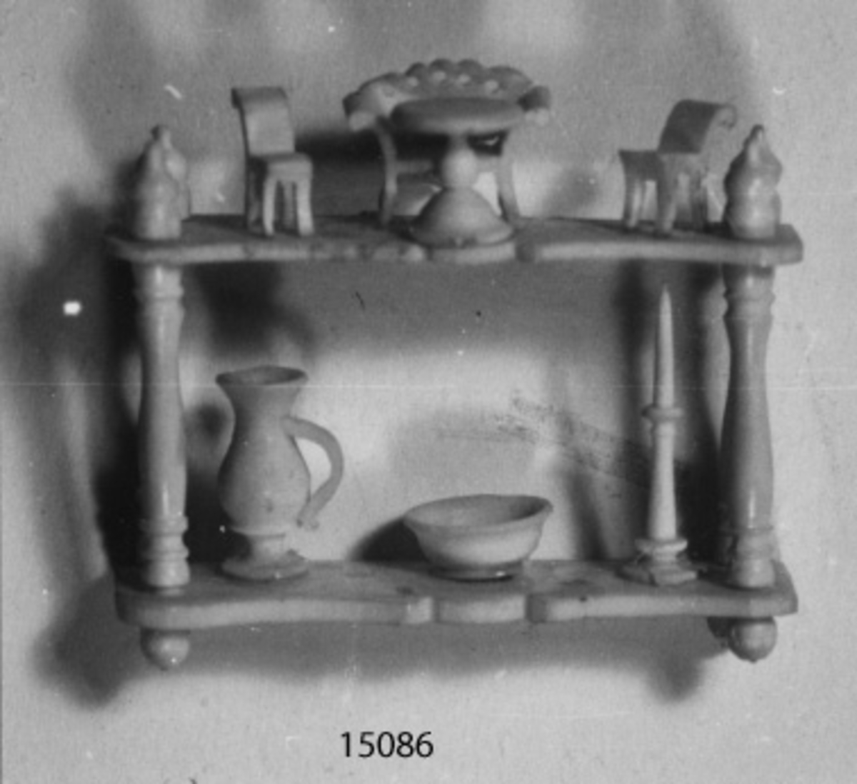 Scrimshaw (modell av atentienne). Sjömansarbete i ben i form av en atenienne med dockmöbler, kanna, skål och ljusstake.