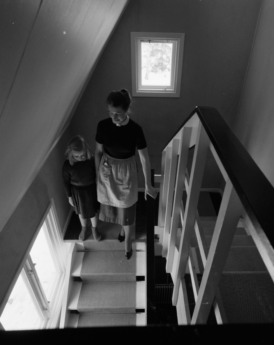 villa Ahlgren
Interiör, kvinna som går med litet barn uppför trappa.