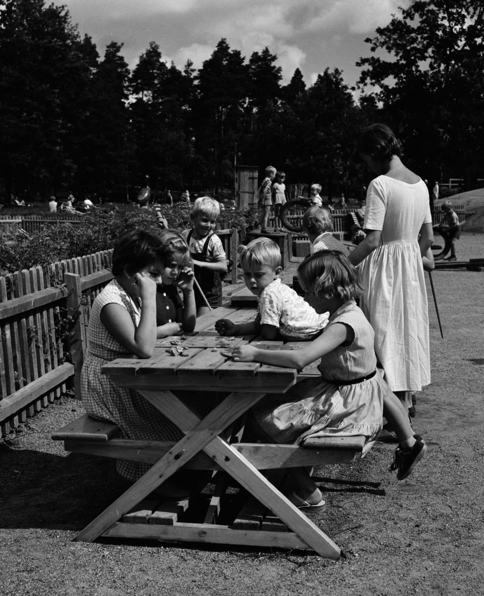 Parkområde
Parklek, kvinnor och barn vid träbord