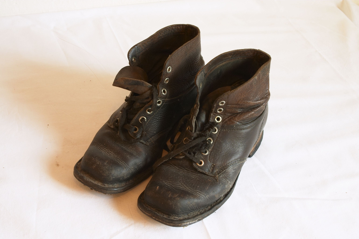 A: Brun/sort beksemstøvler, vanlige med snøring og pløss framme. Dårlig såle under, men ny-sålte hæler. Disse beksemstøvlene er av nyere dato - da de har både spiker og søm i hælene. Størrelse ca 37-38.