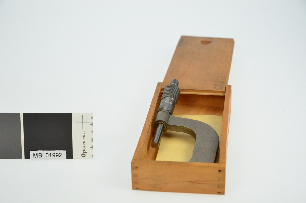 Måleinstrument til å måle tykkelse på materialer. Liggende i treboks.