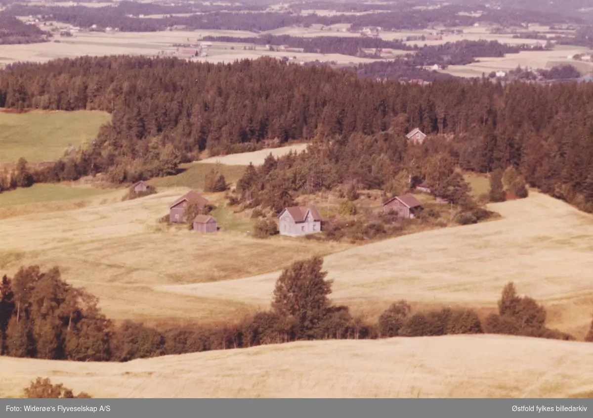 Skråfoto av gården Grøtterud i Eidsberg 11. juli 1963 i forgrunnen, i bakgrunnen Kontra. 
Låven til venstre på bildet er revet.