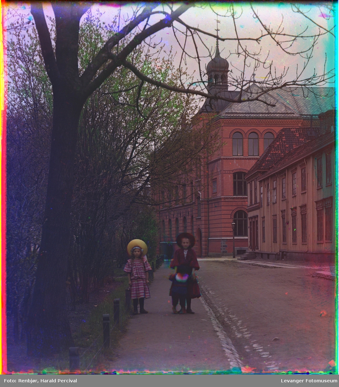 Tre barn går langs en gate i Trondheim. Bakenfor var Trondheim borgerlige realskole, senere Gerhard Schønings skole, nå Thora Storm videregående skole.
