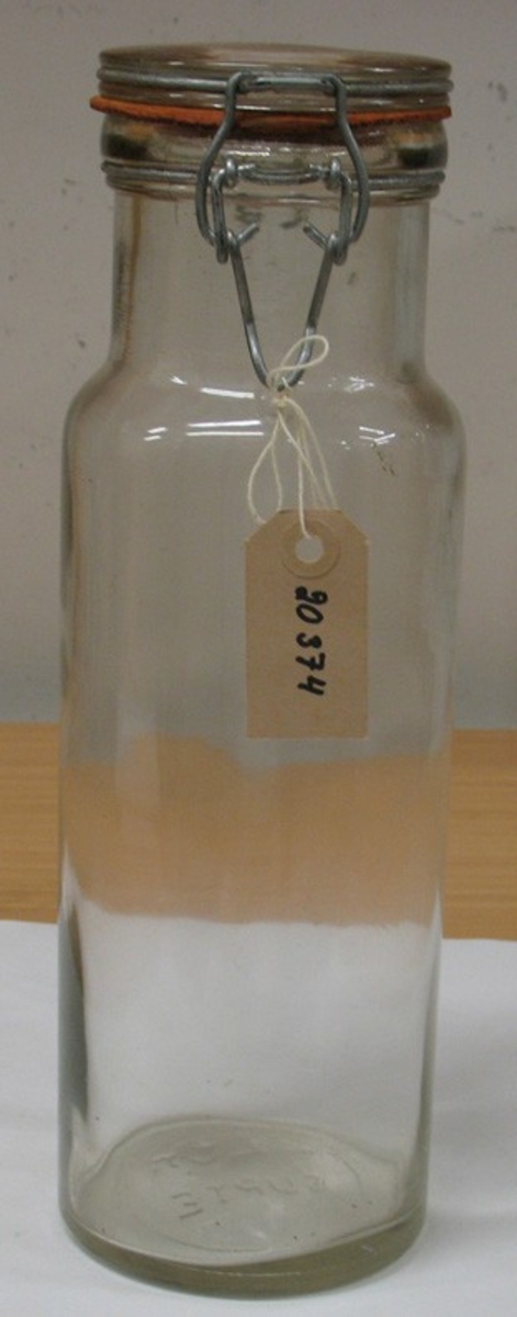 En konserveringsburk av glas med gummiring och stålbygel.

Burken tillvaratogs på vinden i rivningsfastigheten ''Gjuthuset'' på Residentsgatan 13 Vänersborg, som revs den 16 juni 1988.