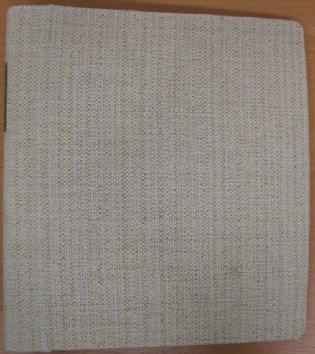 Pärm: ''Praktisk vävbok'' pärm klädd med grovt linne. Pärmen är handskriven och innehåller beskrivning av uppsättningar, varpordningar, mönsterindelningar, inklistrade textilprov m.m.
