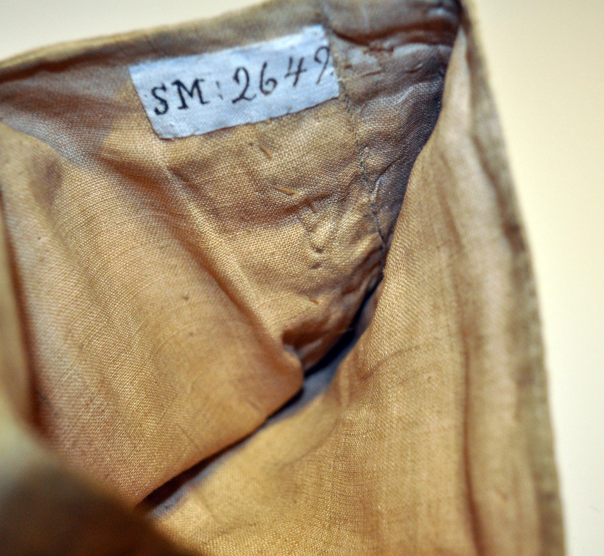 Fra protokollen: Daabsdragt: Hette, livstykke, trøie, linned, fotstykke. Af gul silke, med varepose.

D) Fotpose av samme stoff som lindebåndet (silkedamask), kantet med metallknipling. Fôret med lin.