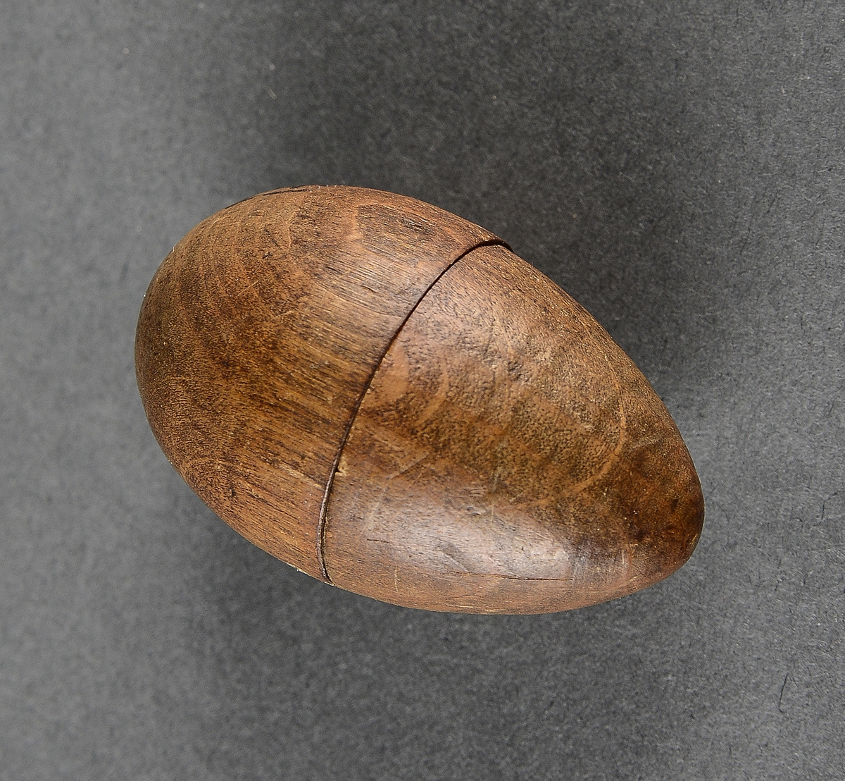 Liten eggformet beholder av metall innlagt i et trefuteral av samme fasong. Inne i  beholderen er det en svamp.