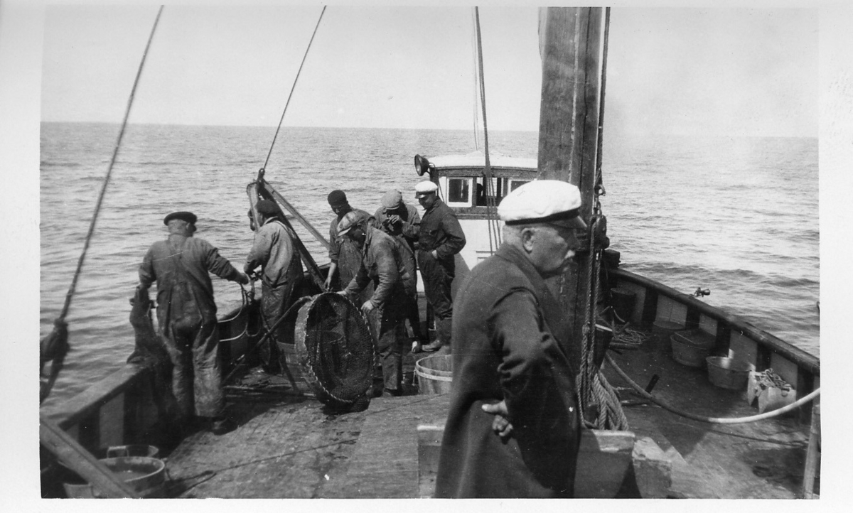 'Akka-expeditionen sommaren 1932: ::  :: 7 st män på däck i färd med att ta hem slädtrålen och nya stora ringar görs klar att sätta ut. Hugo Oldevig (främst?). ::  :: Ingår i serie med fotonr. 2400-2453.'