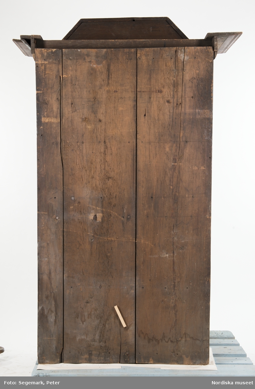 Med nyckel.

Katalogkort:
"Skåpets nedre del m. enkel dörr o lås; en hylla. Övre del med dubbeldörrar och lås med nyckel; en hylla, en skedhållare; två lådor närmast skänken nedanför dubbeldörrarna. På ena dubbeldörrens insida märkt: 1782
på utsidan: 1842 NES AOD
Färg mörkröd, grönt listverk; dekor ljusgul, grönblå, svart."
"1848. N.E.SA.O.D. övermål. ANNO 1788."