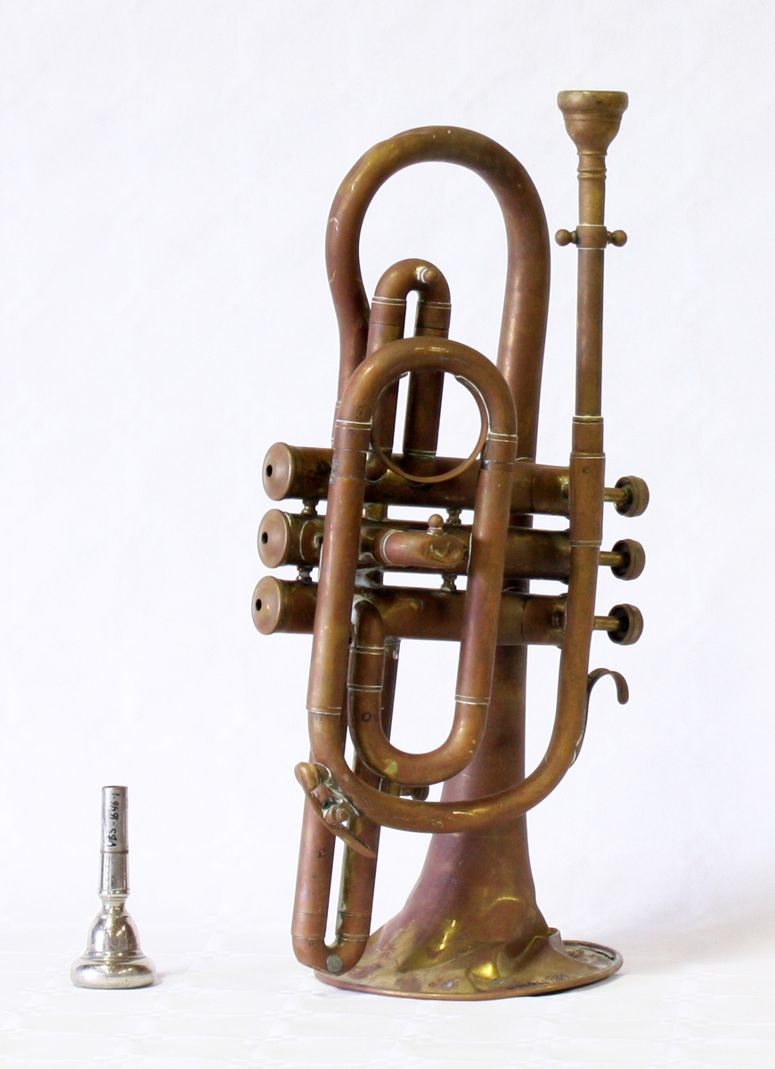Blåseinstrument med tre ventiler, likner delvis en liten trompet i utformingen. Med ekstra munnstykke.