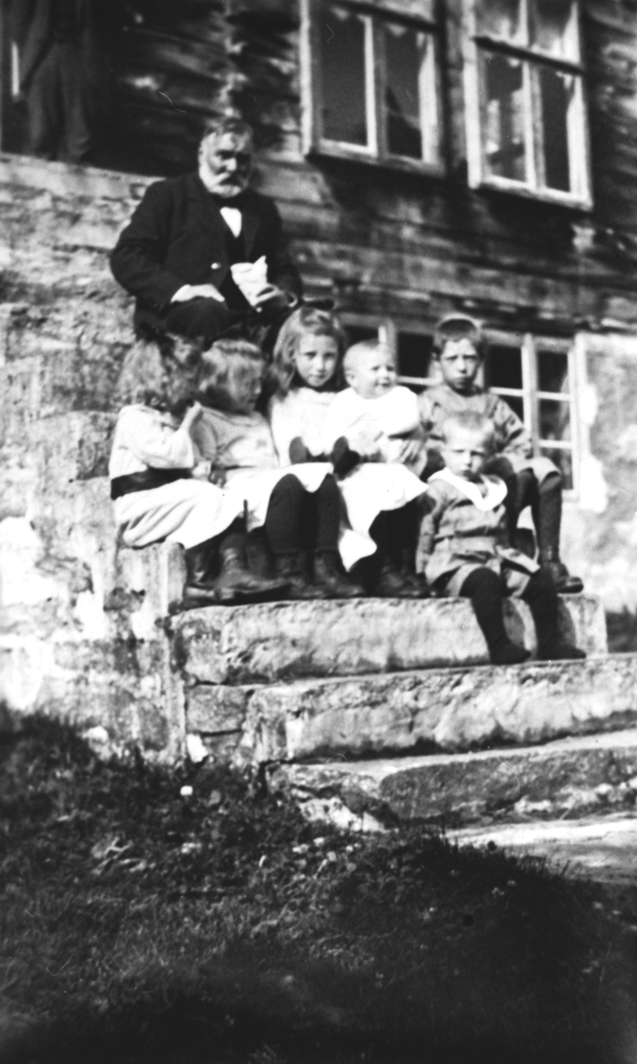 En gruppe barn sammen med Børre Berli på en trapp foran et hus.