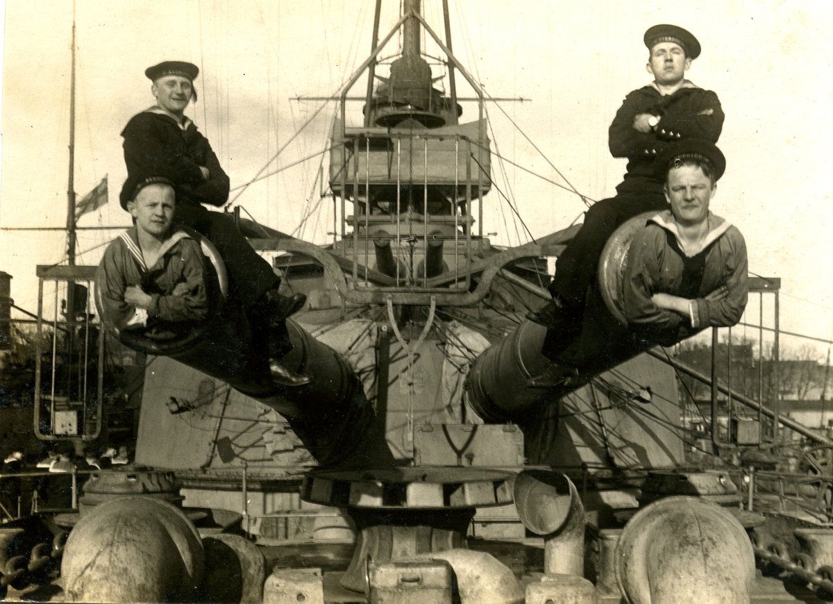 Fyra besättningsmän sitter på/i förliga 28 cm kanonerna på HMS Sverige