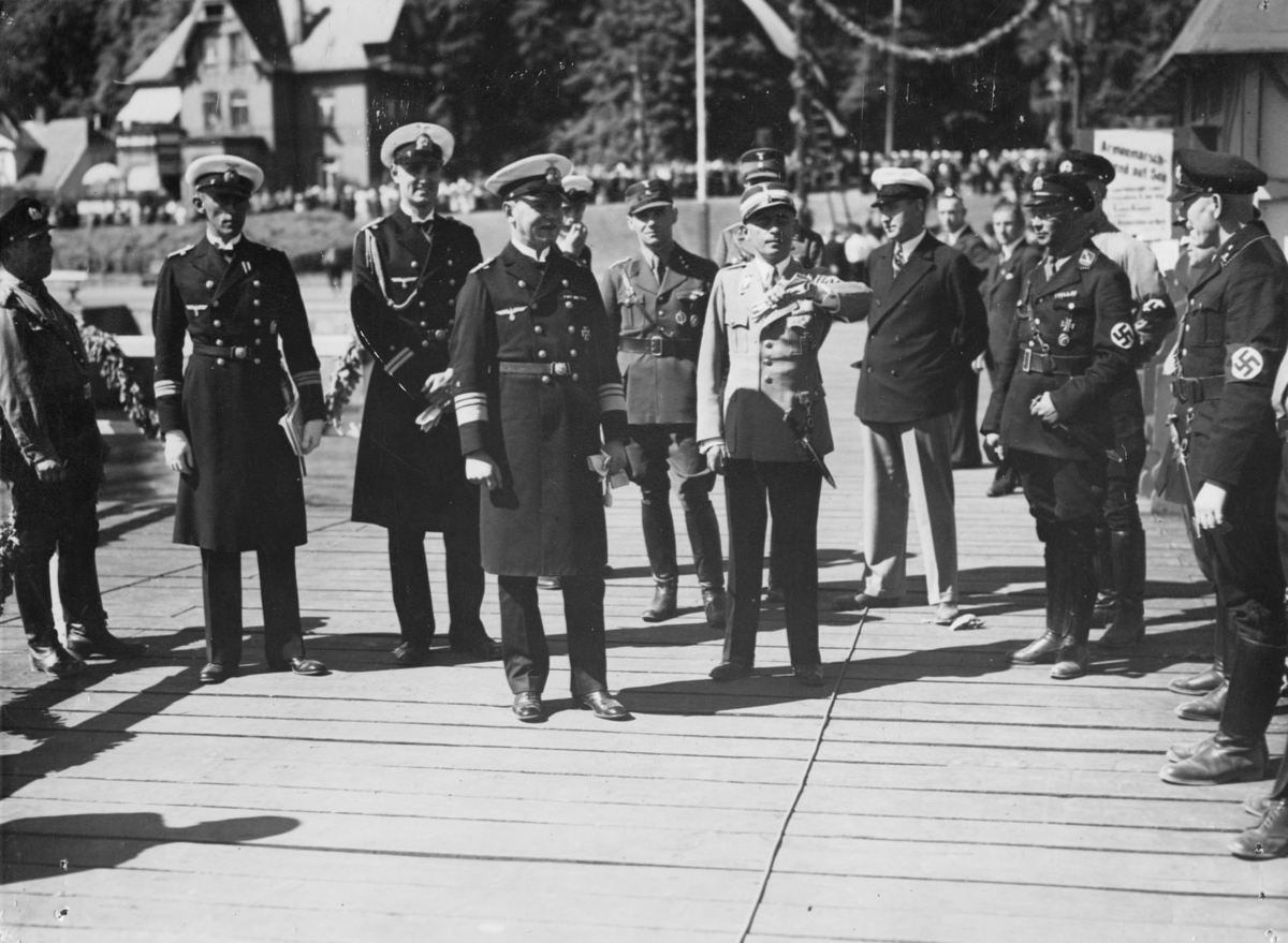 "Reichsportführer [sic] von Tschammer und Osten - han som tittar på armbandsuret - omgiven av amiraler, SA-gruppenfuhrer [sic] och SS-dignitärer vid Kiel-regattans öppnande"