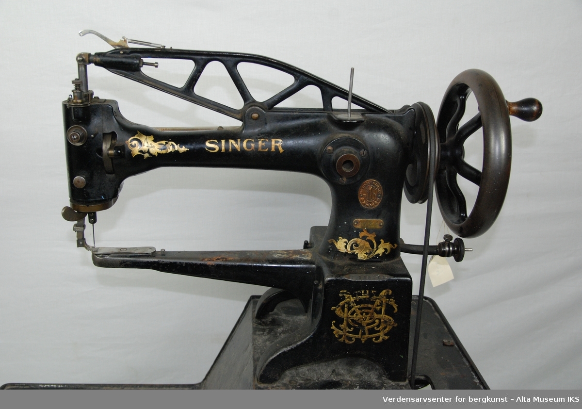 Symaskin med pedal.
Hele rammen til symaskinen er i metall.
Maskinen har en liten skuff.