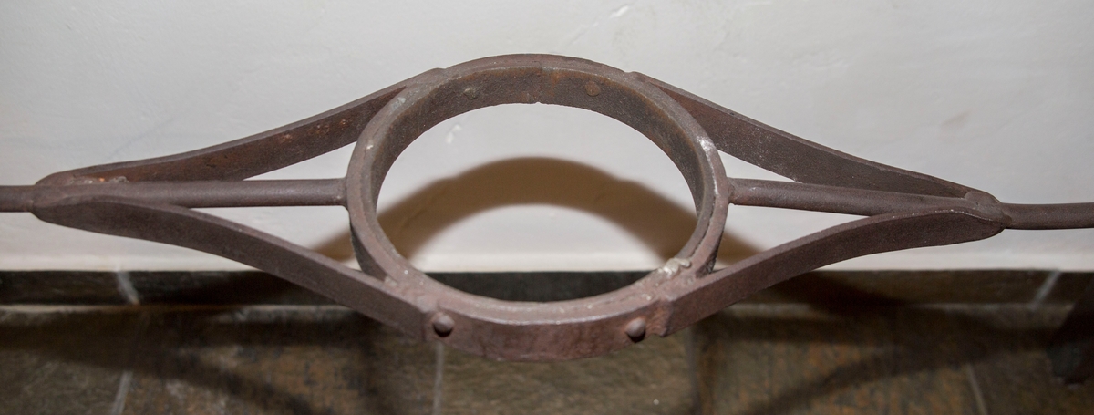 Ring av smijern beregnet på å tre rundt smeltedigler. På to motstående sider av denne ringen er to smale jernstenger. Ytterst, på tvers av den ene stangen er ett håndtak som består av en jernstang som er bøyd slik at den likner en halv firkant.