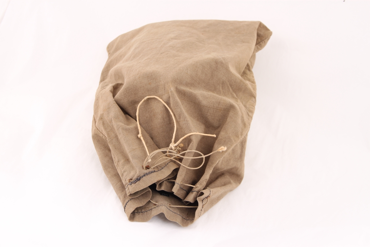 Tøypose i lys brunt vindtøy som lukkes øverst med en snor. Posen har to lommer innvendig.