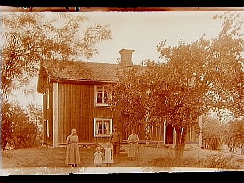 Tvåvånings bostadshus, tre vuxna och två barn framför huset.
Gustaf Andersson
