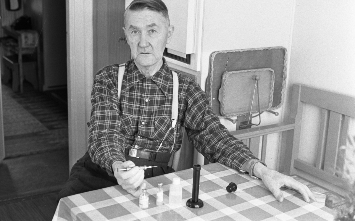 Diabetiker, 155 Ogestad, Fick Guldur 5 februari 1966

En äldre man i en rutig skjorta och hängslen håller en spruta i sin högra hand. Framför honom på bordet står en liten flaska fylld av insulin samt ytterligare två flaskor. Mannen har diabetes.