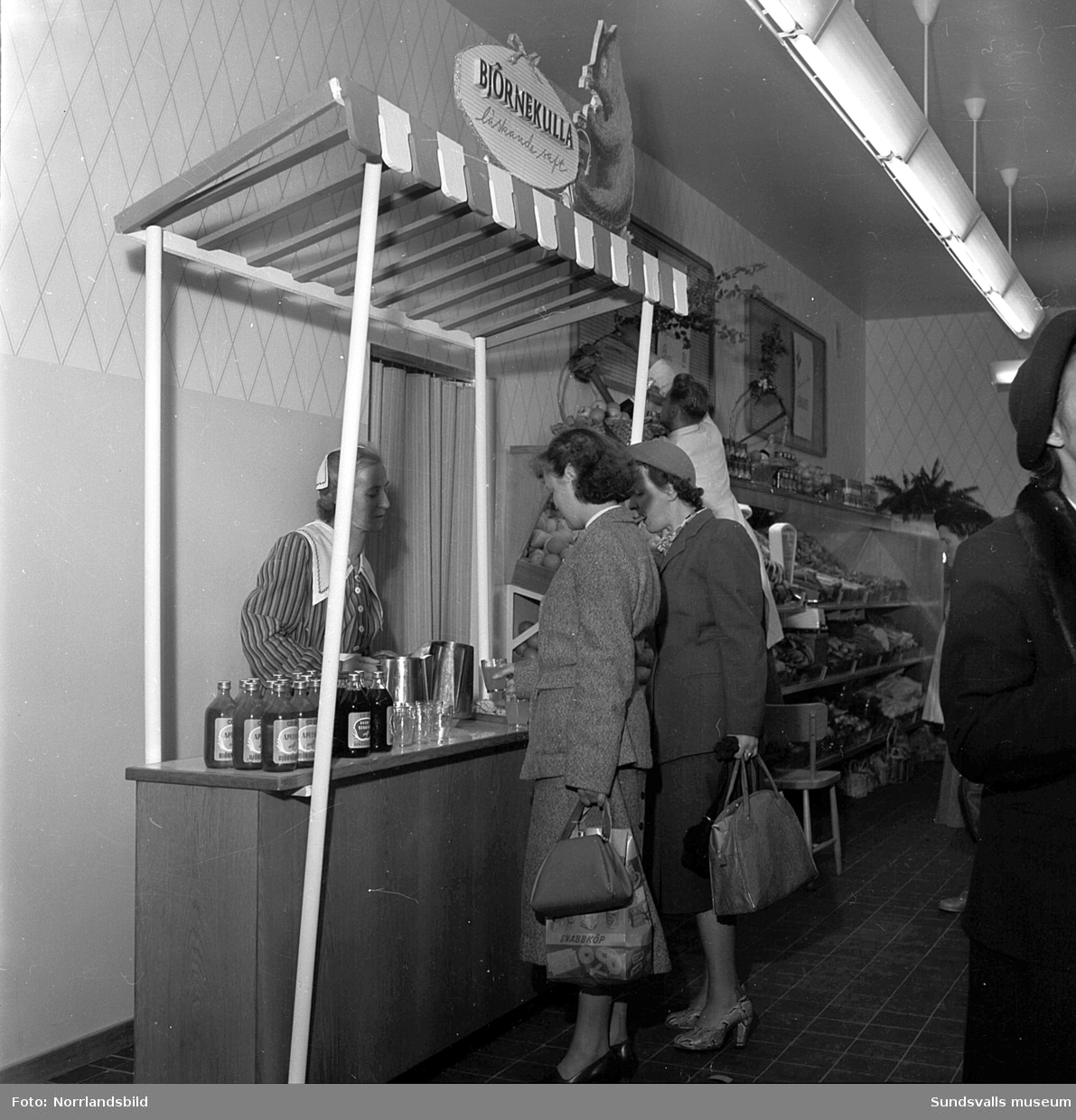 Konsums snabbköp vid Bankgatan har byggts ut 1952 och en kund är sångerskan Alice Babs som inspekterar fruktavdelningen och handlar för fem kronor och femtiosju öre.