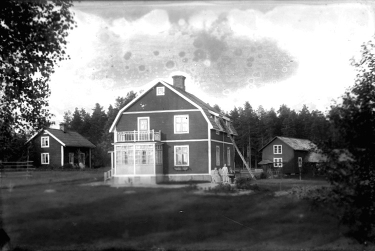Tvåvånings villa i Rönneshytta, dit läraren i Fridhems skola, Norrbyås socken flyttade.
Familjegrupp 3 personer framför villan.