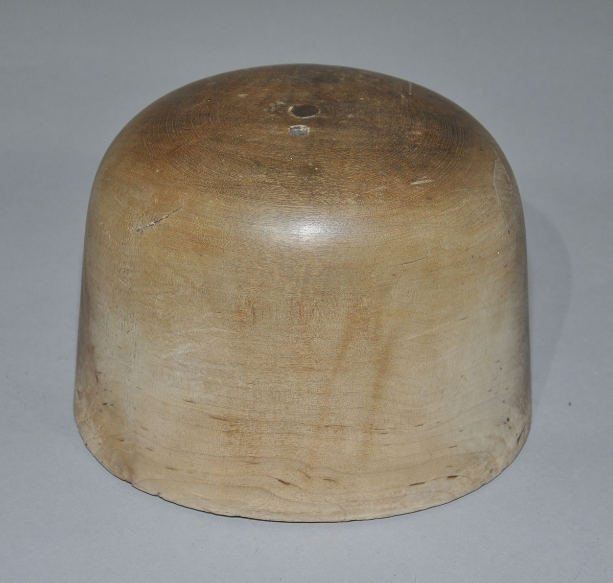 Hatteblokk skåret ut av ett trestykke. Hatteblokken har en sylinderform hvor toppen er avrundet.