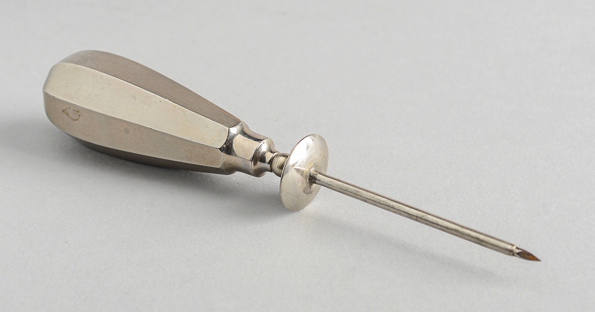 Håndtak med sterk nål med trekantet spiss, liggende i et rør med mansjett. Nålen kan trekkes ut av røret.
